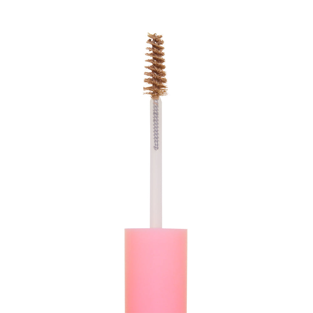 A close-up of glamnetics 3-in-1 Brow It All spoolie brush with brown brow gel on the bristles, featuring a pink handle, isolated on a white background.