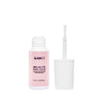 A small glamnetic Brush-On Nail Glue bottle with a pink label sits by its white cap. The upright brush applicator, coated in glue, is ready for salon-style nails or applying glamnetic Press On Nails.