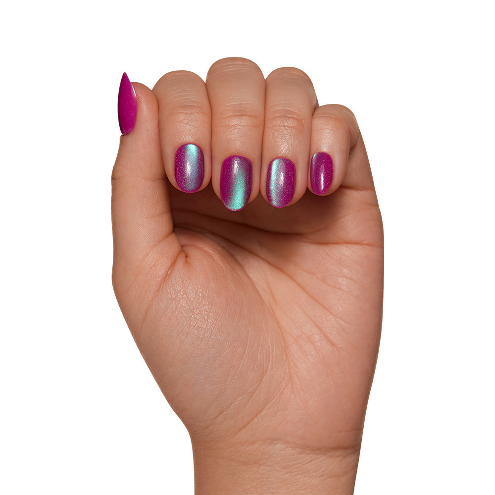 A hand with nails painted in glamnetics Berry Fizz Nail Set features a metallic pink and blue ombre polish with a velvet finish, highlighted against a white background to show its iridescent magenta hue.