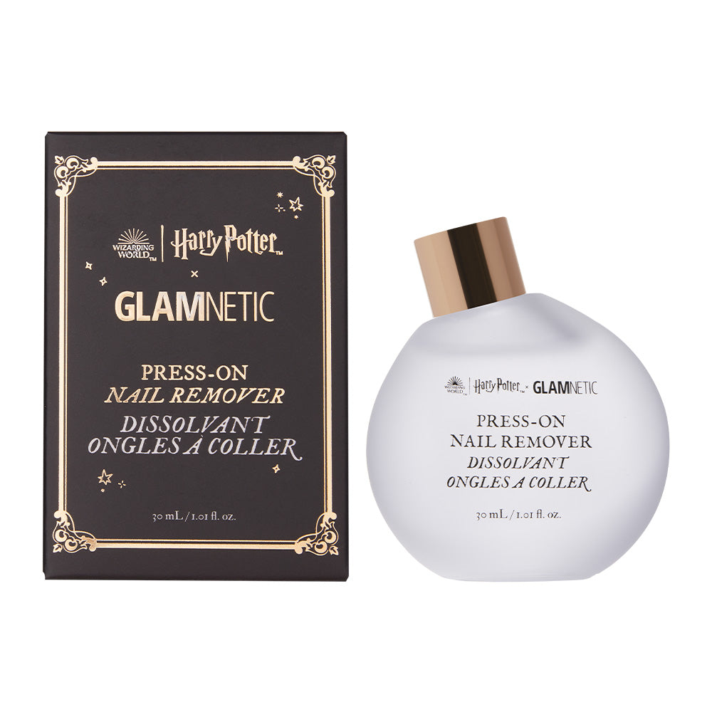 A 30ml bottle of glamnetic Harry Potter™ Press-On Nail Remover, an acetone-free formula, is displayed beside its decorative black and gold box. The white bottle has a gold cap and black front text.