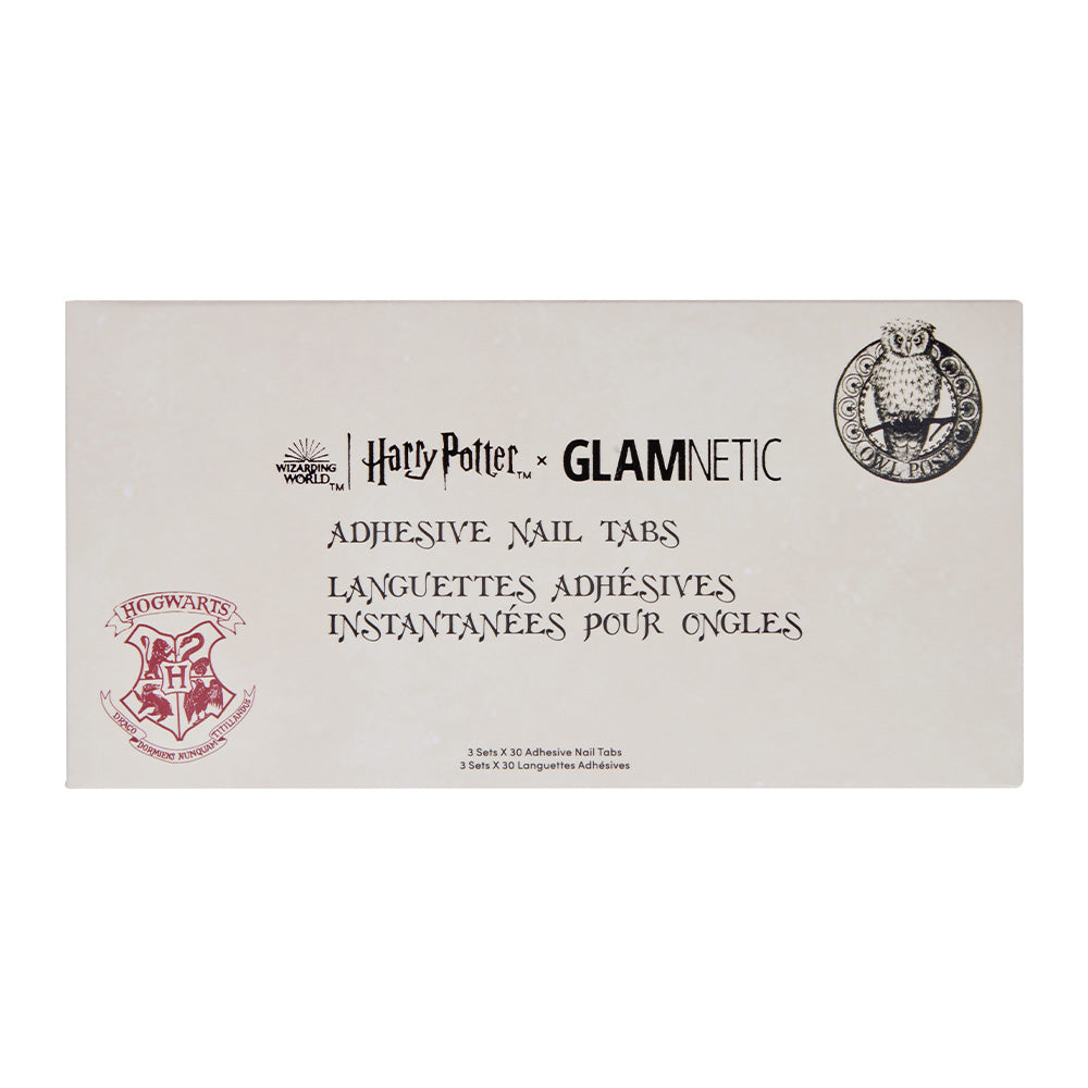 A rectangular box labeled Harry Potter™ Adhesive Nail Tabs by glamnetic features Hogwarts and owl logos, with English and French text on a beige background, hinting at magical press-on nails inside.