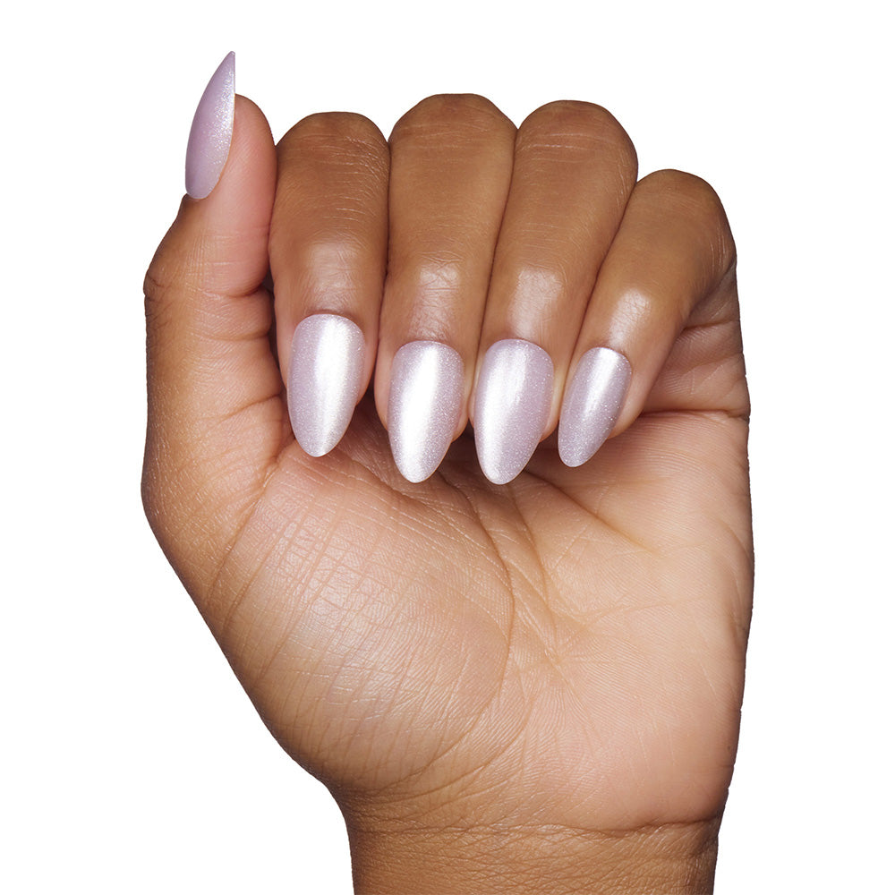 A hand with medium-brown skin displays short, almond-shaped nails painted with shimmery pale pink polish from the glamnetic Selenite set against a white background.