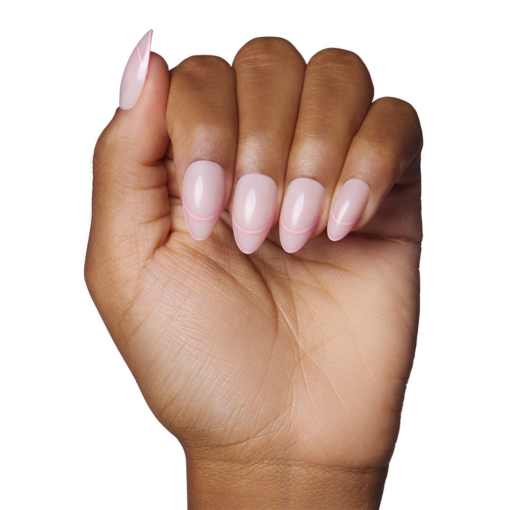 A hand with medium brown skin displays short, almond-shaped nails painted with glamnetics Hot Take—a pale pink polish with a glossy finish. The well-manicured nails are shown against a white background, highlighting the elegant look.