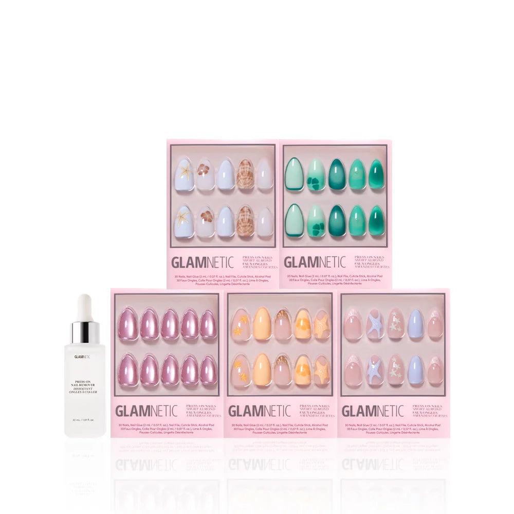 Five sets of glamnetic Ann’s Cove press-on nails in pink boxes, showcasing colorful and 3D nail art designs, are arranged in two rows. A white dropper bottle sits to the left of the display.