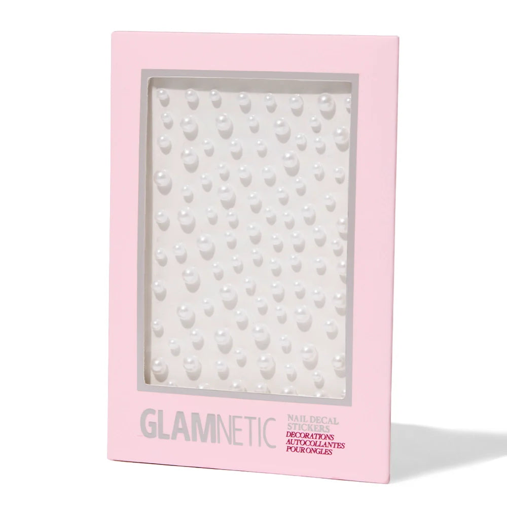 A pink-bordered package from glamnetic labeled Pearlfect Nail Decal Stickers contains a sheet of small, raised pearl-like 3D nail stickers arranged in neat rows.