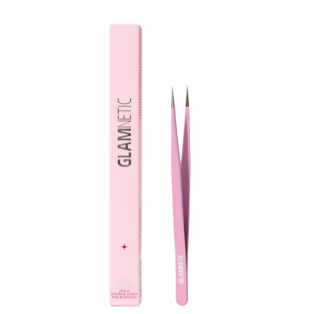 A pair of pink glamnetic Nail Decal Tweezers with pointed tips stands beside a matching pink rectangular box labeled glamnetic on a white background.