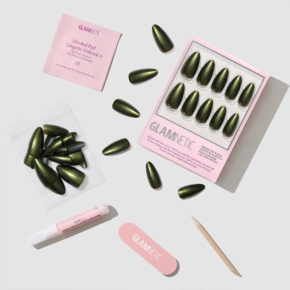 The Cutie Pine press-on nails by glamnetic, plus a pink nail file, wooden cuticle stick, glue tube, alcohol pad, and extra nails with glamnetic branding, are arranged on a white surface.