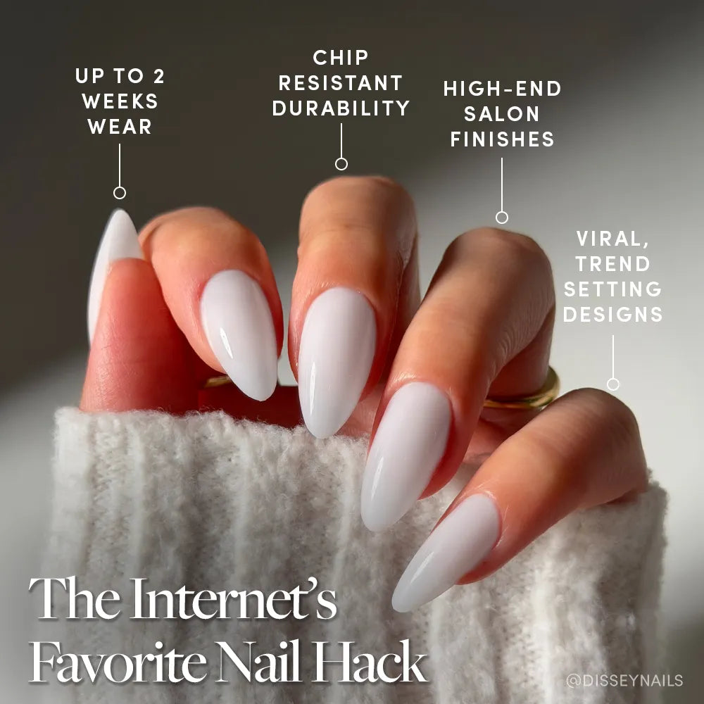A hand with long, almond-shaped nails wears "Clouded" by glamnetic—a milky pale grey mani. Text highlights up to 2 weeks wear, chip-resistant durability, salon finish, and viral trendsetting design. A sweater sleeve partly covers the hand.