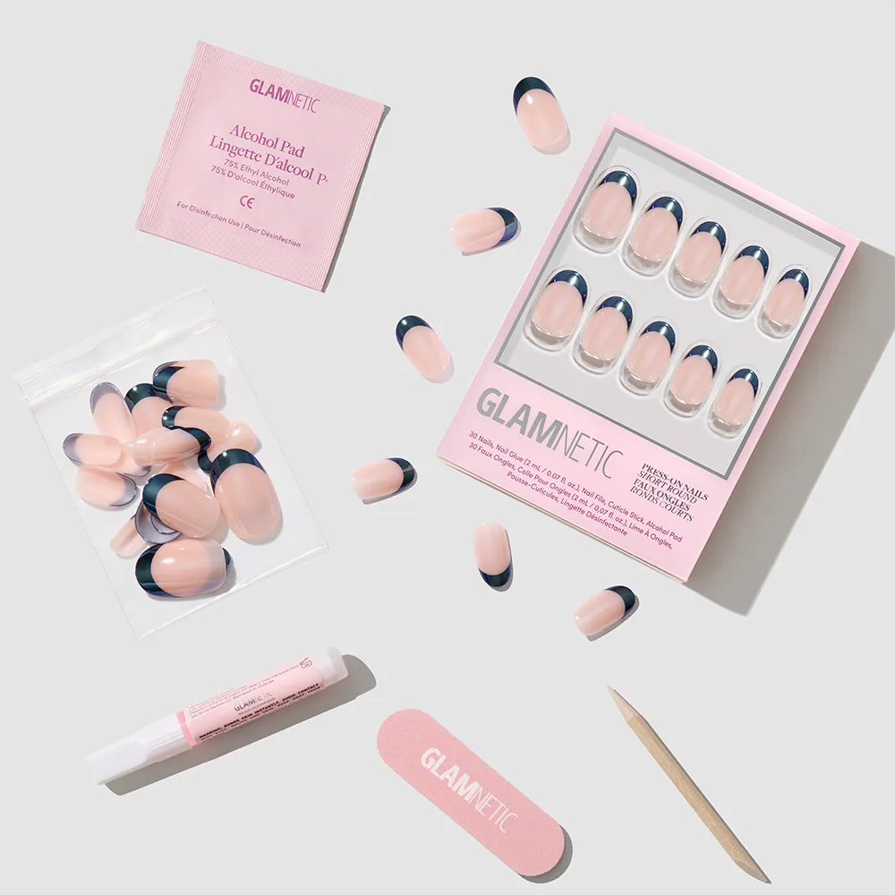 A set of glamnetic Onyx Glaze pink press-on nails with navy blue French tips, glossy finish, nail glue, file, cuticle stick, alcohol pad, and extra nails are arranged neatly on a light background.