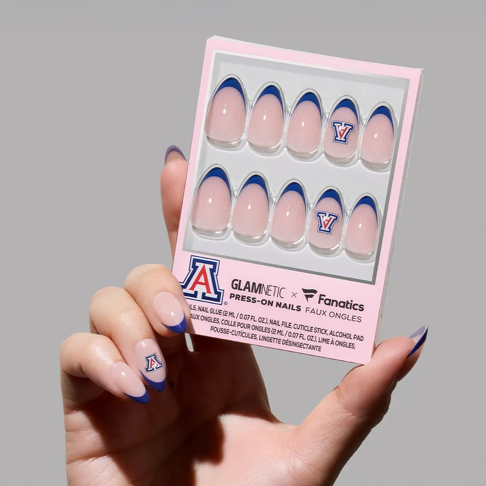 A hand displays the glamnetic Arizona Wildcats Press-On Nail Set featuring pink bases, navy French tips, and the team’s A logo—salon-quality nails in branded packaging, perfect for fans to show their Wildcats pride.