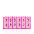 Six pink rectangular boxes of glamnetic's Ultimate Lash Wardrobe are lined up, each with a clear lid showcasing voluminous black lashes inside. Both the boxes and the glamnetic brand name are prominently visible.