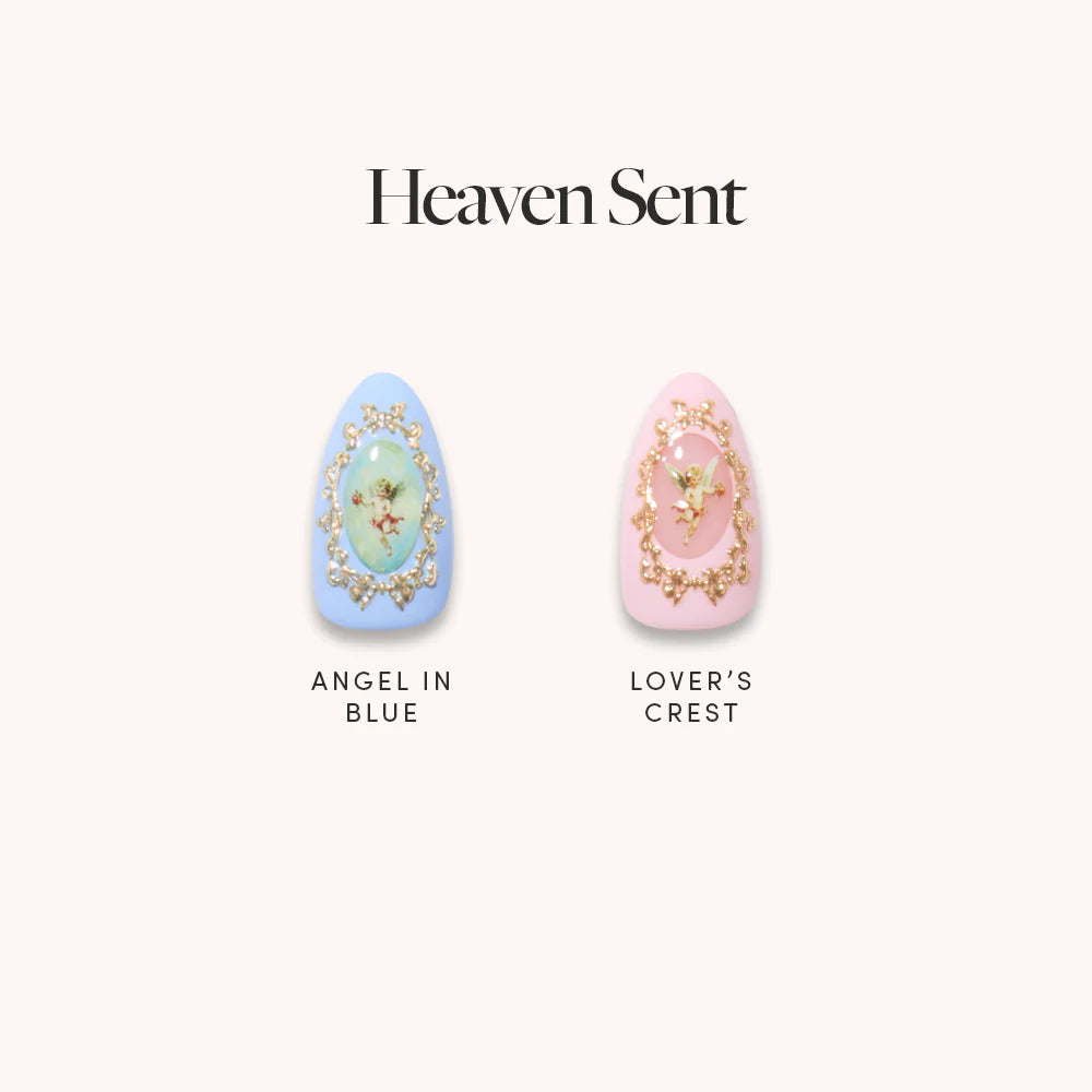 Two cherub-themed nails from glamnetic’s “Heaven Sent”: Left is “Angel in Blue,” a blue almond set with 3D gold and an angel; right is “Lover’s Crest,” a pink nail with gold trim and angel art. Text above: Heaven Sent.