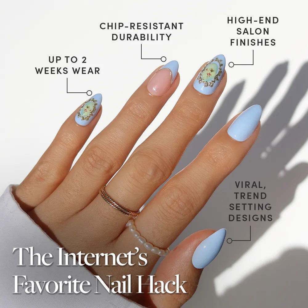 A hand with long, almond-shaped nails in glamnetic's Angel in Blue—pastel blue and nude with 3D gold accents. Enjoy chip-resistant durability, high-end finishes, viral designs, and up to two weeks of wear.