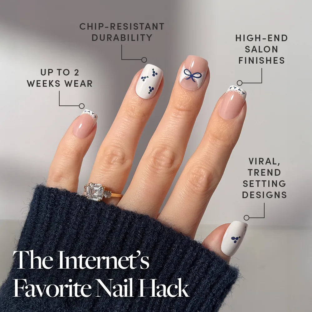 A manicured hand with Blue A Kiss squoval press-on nails by glamnetic, featuring minimal dots, a bow, lace, and blueberry accents. Chip-resistant, long wear, salon-quality and trendy. Text: The Internet’s Favorite Press On Nail Hack.