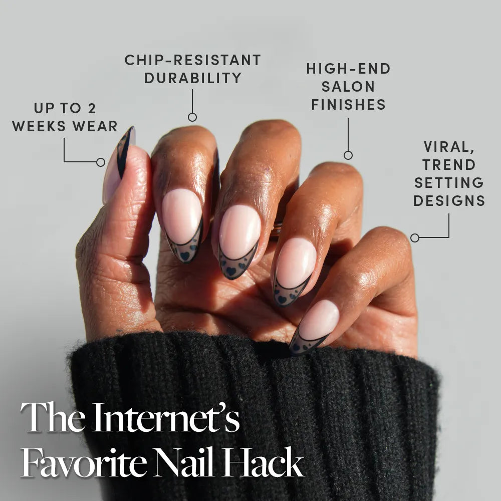 A hand with short almond nails features glamnetic's Love Noir: black heart nail art and chic French tips. Enjoy up to 2 weeks wear, chip-resistant, high-end finishes, and trendy designs. The Internet’s Favorite Nail Hack.