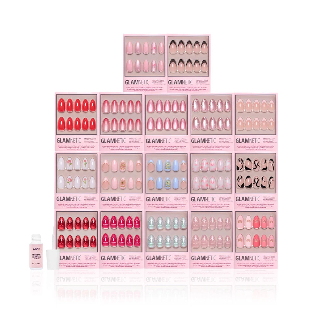A pyramid display of 15 pink Glamnetic "The Almond Crush" boxes shows off short almond press-on nails with 3D art in red to pale pink shades, plus a nail glue bottle on the left.