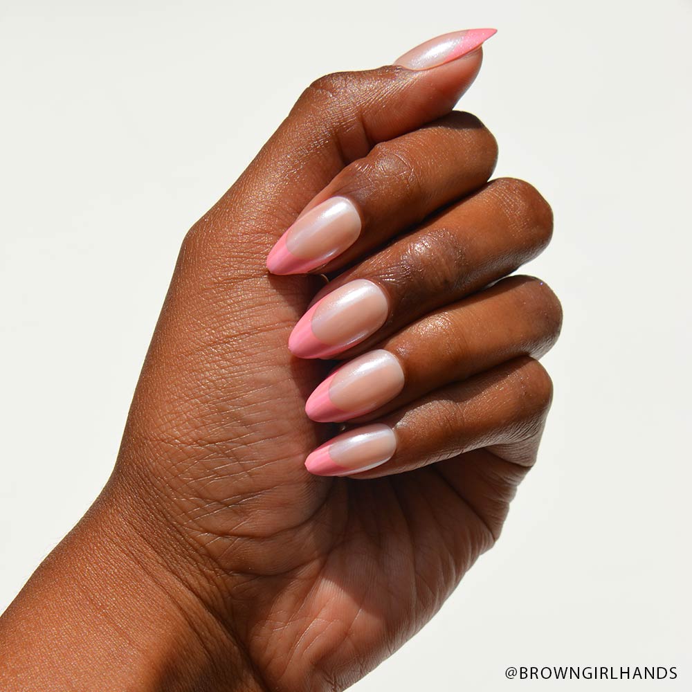 A hand with medium brown skin displays almond-shaped nails featuring glamnetics Bubble Gum Glaze French tips over a natural base. The background is plain white, with @BROWNGIRLHANDS in the bottom right corner.