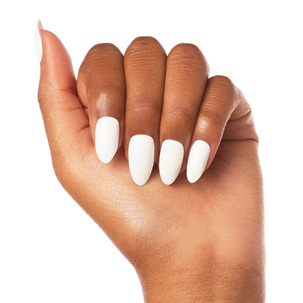 A hand with medium brown skin displays Angel by glamnetic—vegan, glossy white press-on nails in a chic almond shape. Fingers are slightly curled against a plain white background.