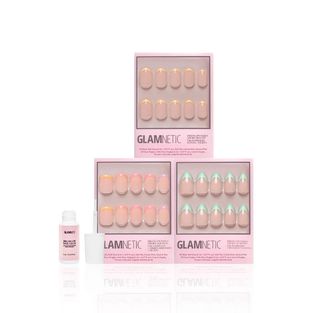 Three sets of glamnetic À La Ann press-on nails in pink boxes, each with colorful French tips, are stacked together. In front on the left, an open bottle of nail glue is ready for salon-quality durability at home.