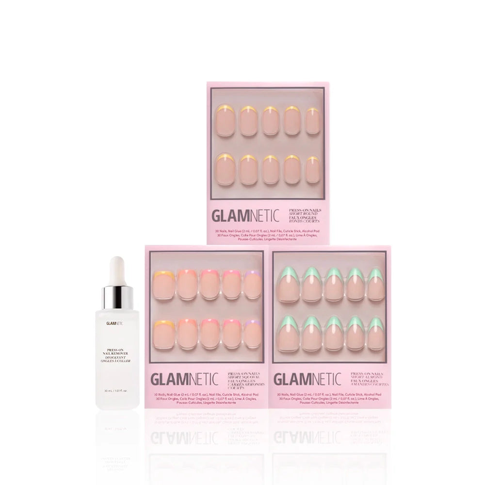 Three boxes of glamnetic À La Ann press-on nails in various pastel French tip designs are stacked beside a white serum bottle with a dropper, all arranged against a clean white background.