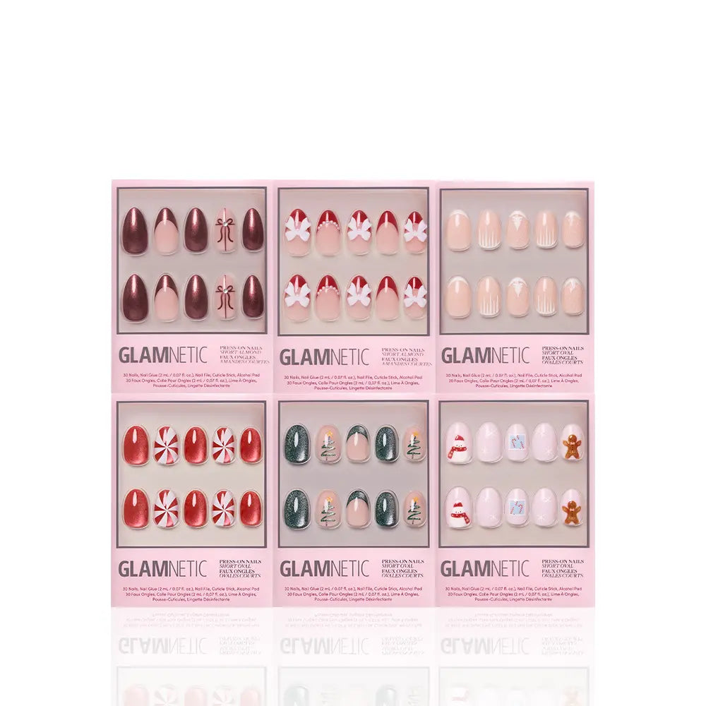 Six boxes of glamnetic All Decked Out winter press-on nails are arranged in two rows, displaying festive red, green, and white holiday designs with snowflakes, candy canes, Christmas trees, and gingerbread men for a cheerful look.