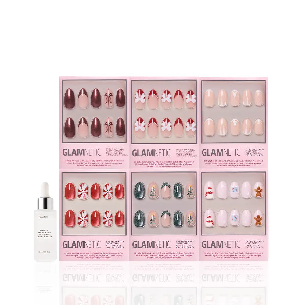 Six boxes of glamnetic All Decked Out winter press-on nails with festive holiday designs are arranged in two rows, with a white bottle of glamnetic cuticle oil to the left, all displayed on a white background.