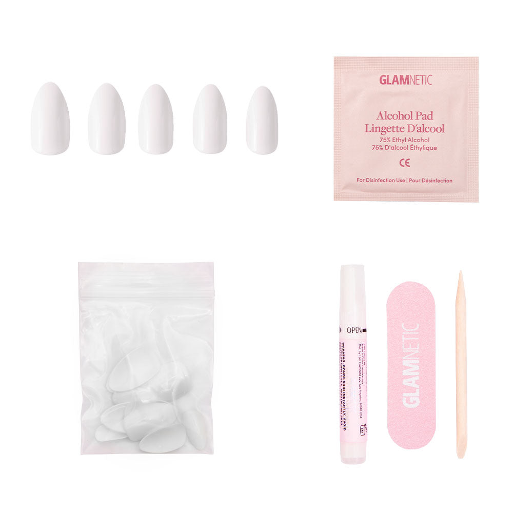 The glamnetic Angel press-on nail kit includes five white almond-shaped nails, an alcohol pad, extra nails in a resealable bag, nail glue tube, pink file, and wooden cuticle stick—displayed on a white background.