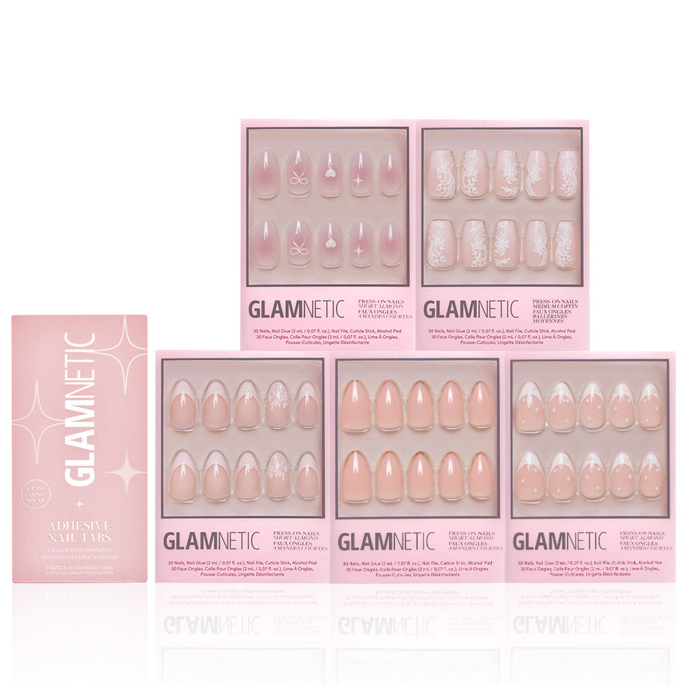 Six boxes of glamnetic Anns Sweethearts press-on nail sets, featuring nude and pink shades with short almond shapes, French tips, and delicate white designs, are arranged neatly against a white background.