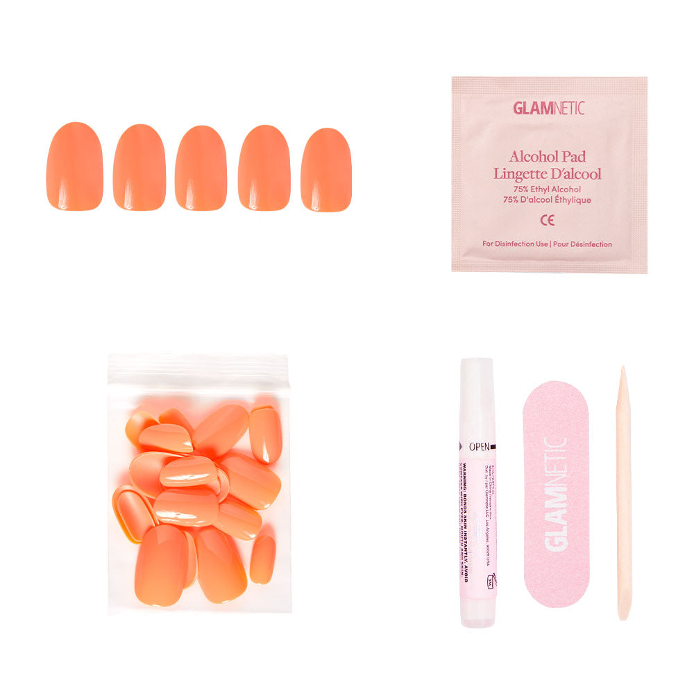 The Apricot Press-On Nail kit by glamnetic features five vibrant orange nails, an alcohol pad, glue, a pink nail file, and a wooden cuticle stick arranged on a white background.