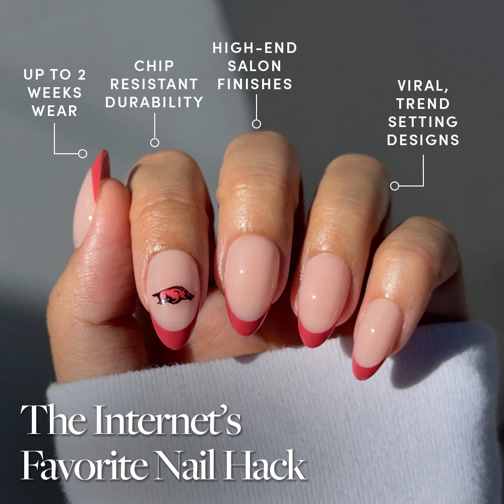 A hand with neatly manicured nails features the Arkansas Razorbacks Press-On Nail Set by glamnetic, showcasing pink tips and an eye design. Enjoy up to 2 weeks wear, chip resistance, salon finish & trendy styles—perfect for game day. The Internet’s Favorite Nail Hack.