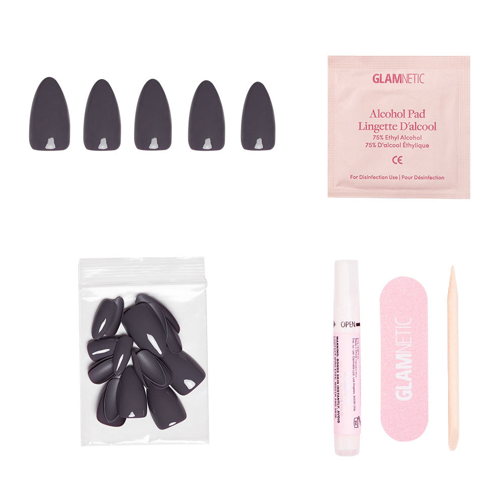 Ash Gray almond press-on nails from glamnetic’s Fall Forest Collection, featuring black nails, alcohol pad, extra nails bag, nail glue pen, pink file, and cuticle stick displayed on a white background.