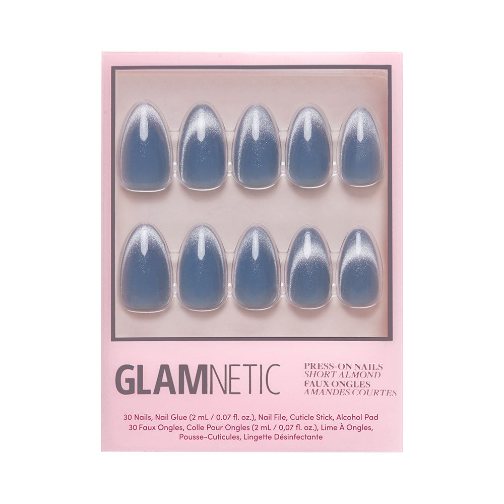A box of glamnetic Baby Blues press-on nails in short almond shape, shown in three rows. The glossy pastel blue nails have a velvet metallic finish; package includes nail glue, file, cuticle stick, and alcohol pad.
