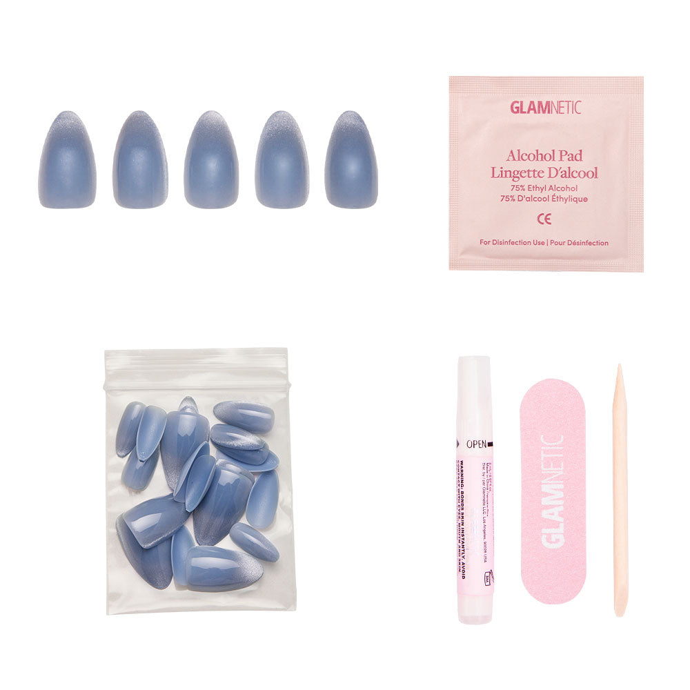 The glamnetic Baby Blues set includes pastel blue press-on nails with a velvet metallic finish, nail glue, extra nails, an alcohol pad, pink file, and wooden cuticle stick—all displayed on a white background.