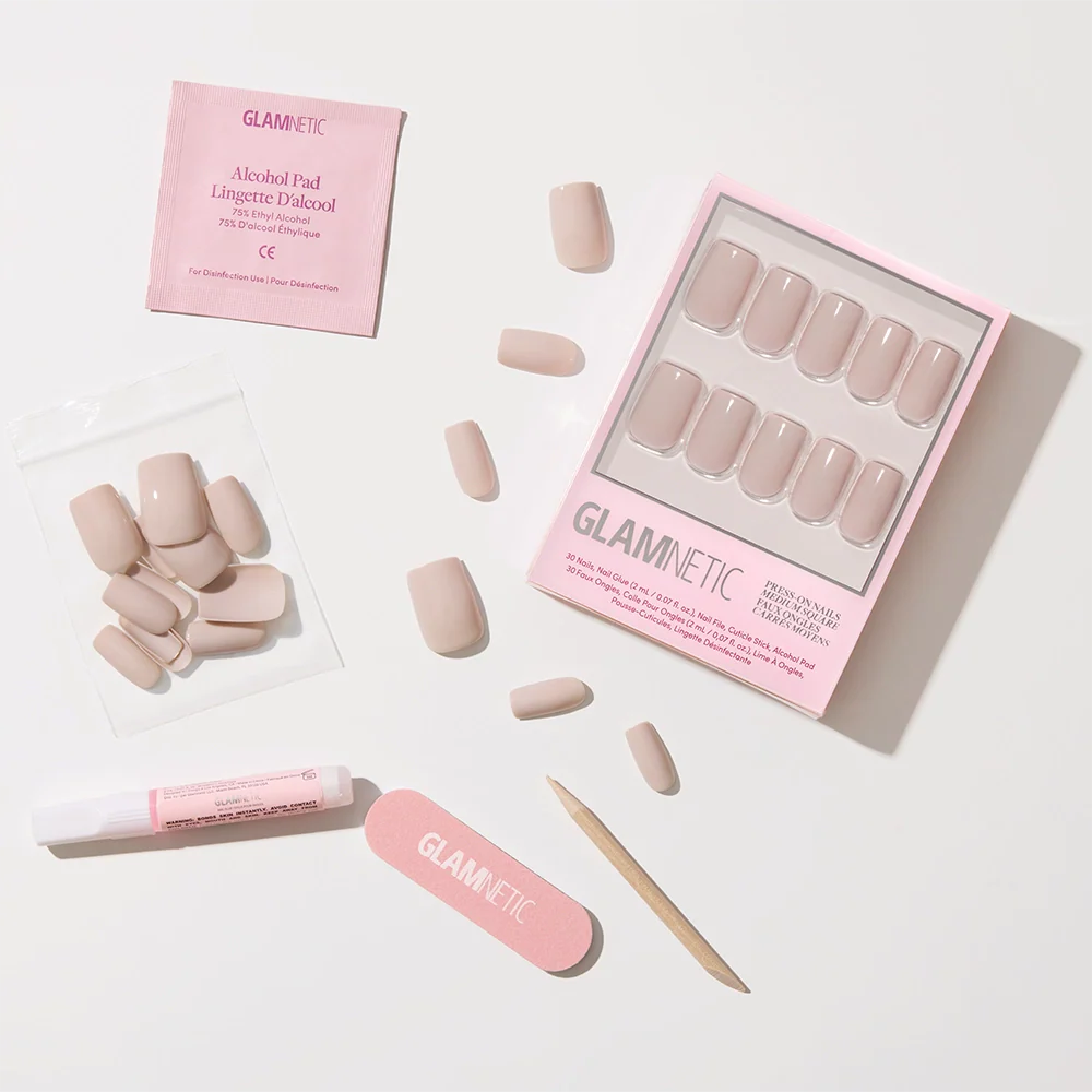 Bare Bliss by glamnetic features nude medium square press-on nails with an opaque finish, a pink nail file, cuticle stick, glue, alcohol pad, and extra nails—all neatly arranged on a white background.