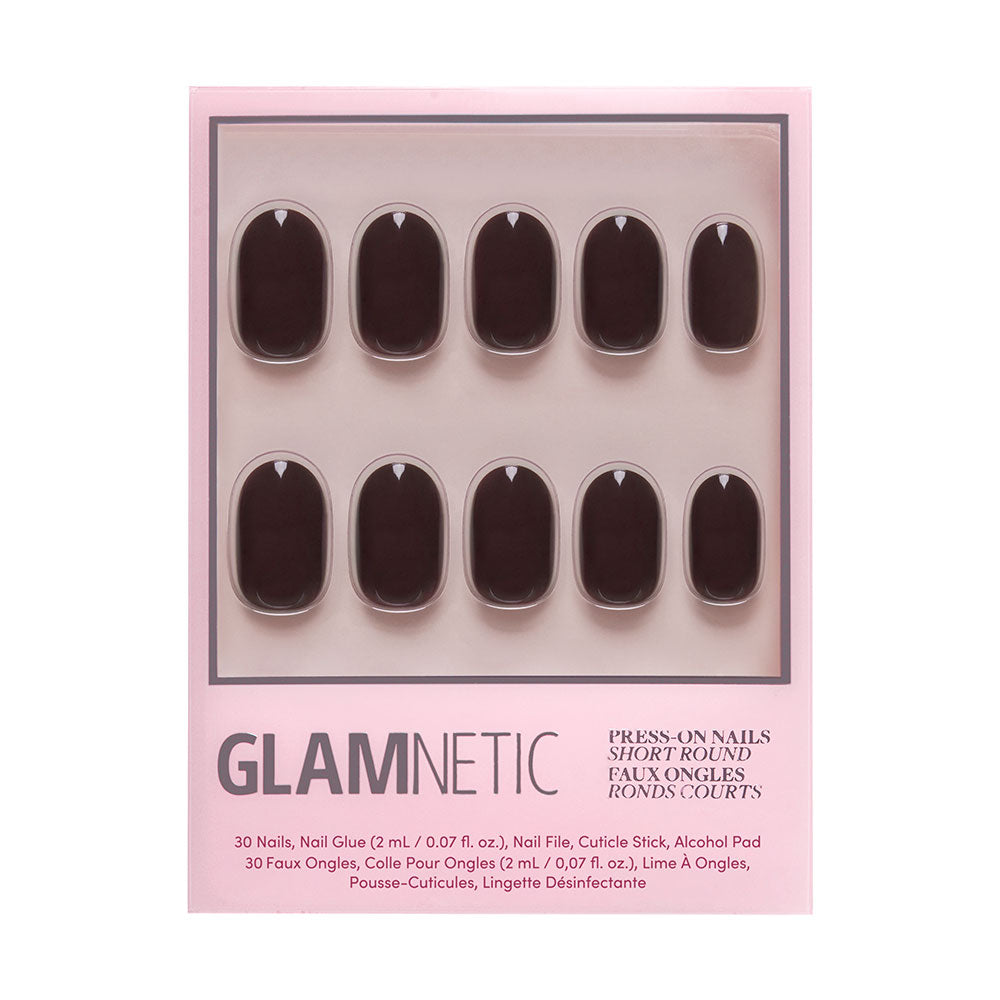 A set of glamnetic Bark Brown short round press-on nails in dark brown with a glossy finish, arranged in two rows inside a pink box. Includes nail glue, file, cuticle pusher, and alcohol pad.