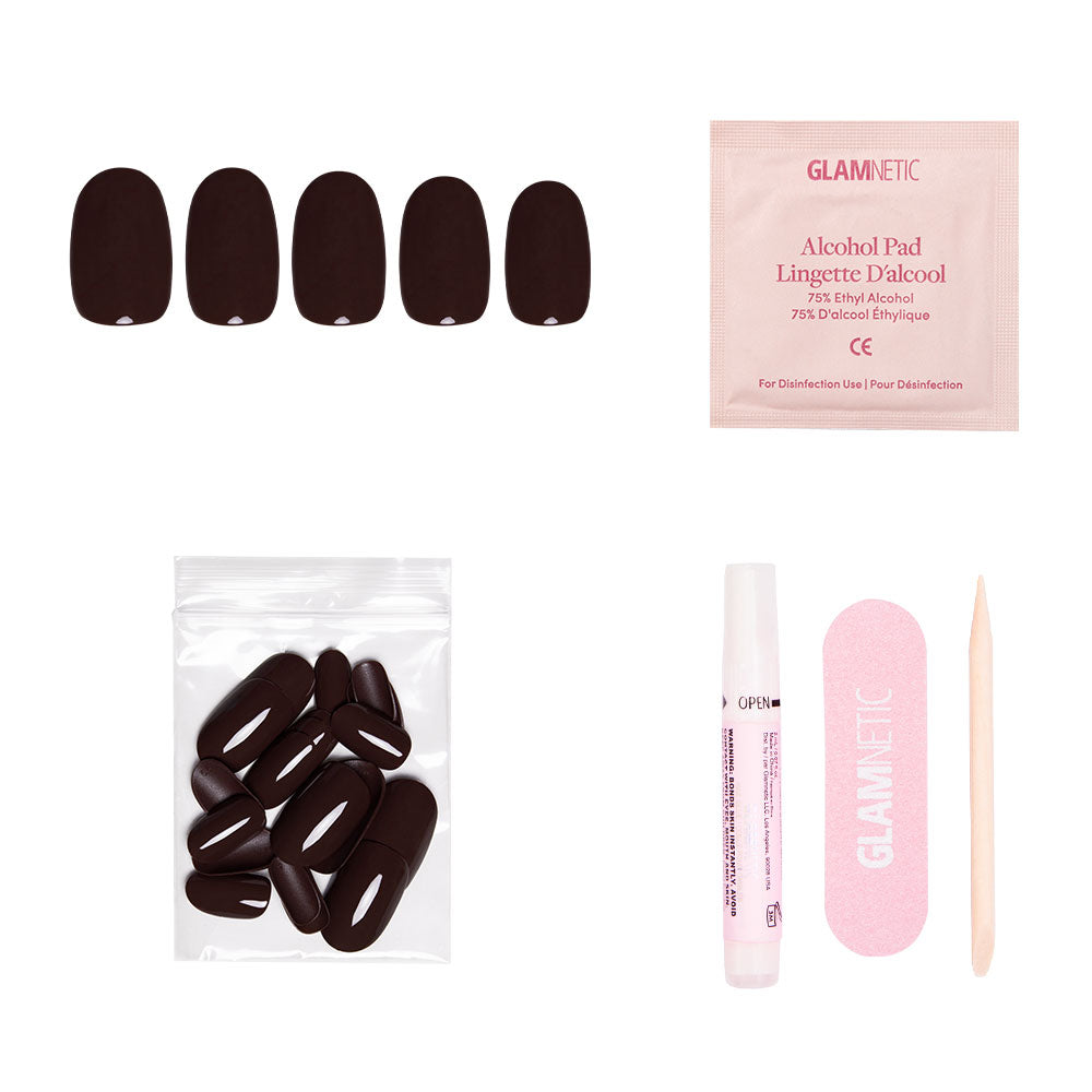 The glamnetic Bark Brown set includes glossy finish nails, extra nails in a plastic bag, an alcohol pad, nail glue tube, pink nail file, and wooden cuticle stick—all arranged on a white background.