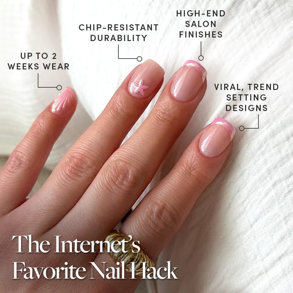 A hand with manicured nails in soft pink chrome tips and a white bow shows off glamnetic’s Blush Dunes Press-On Nail Set, offering up to 2 weeks wear, chip-resistant durability, salon-quality finish, and viral trendy designs.