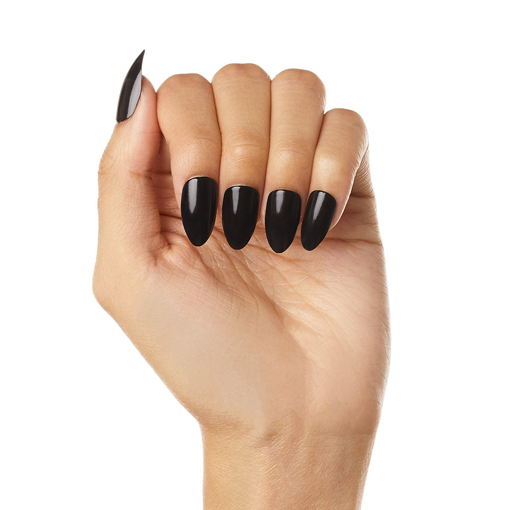 A hand with medium skin tone shows off long, almond-shaped nails painted in glossy black Boba by glamnetic—vegan and cruelty-free—against a white background.