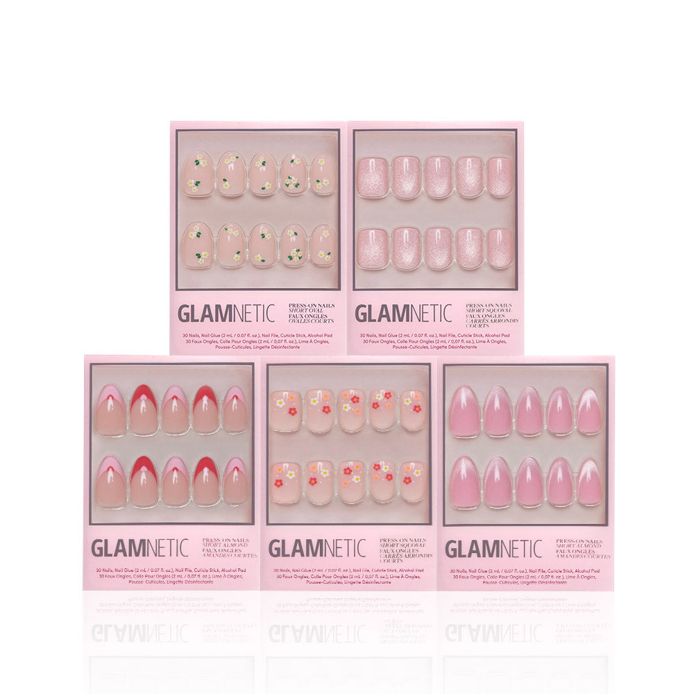 Five boxes of glamnetic Budding Romance Glossy Nail Set are displayed, each containing ten Short Almond press-on nails in various pink designs, including florals, solid pinks, and pink tips, neatly arranged against a white background.
