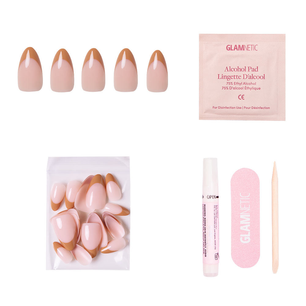 The glamnetic Café Crème set features reusable press-on nude nails with cozy brown French tips, plus extra nails, nail glue, a pink nail file, wooden cuticle stick, and alcohol pad—all arranged on a white background.