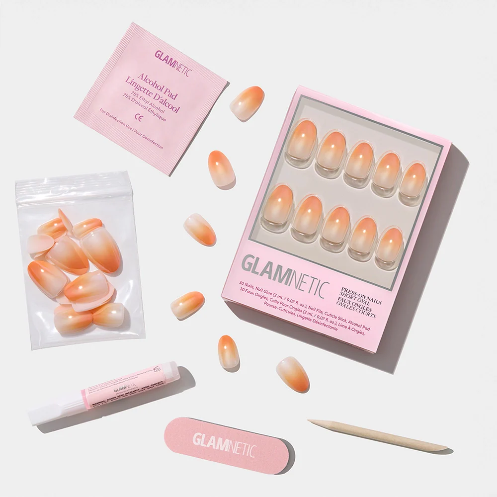 The glamnetic Candy Corn set features orange ombré nails with a peach fade, plus a nail file, cuticle stick, nail glue, alcohol pad, and extra nails—ideal for Halloween flair—all shown on a crisp white background.