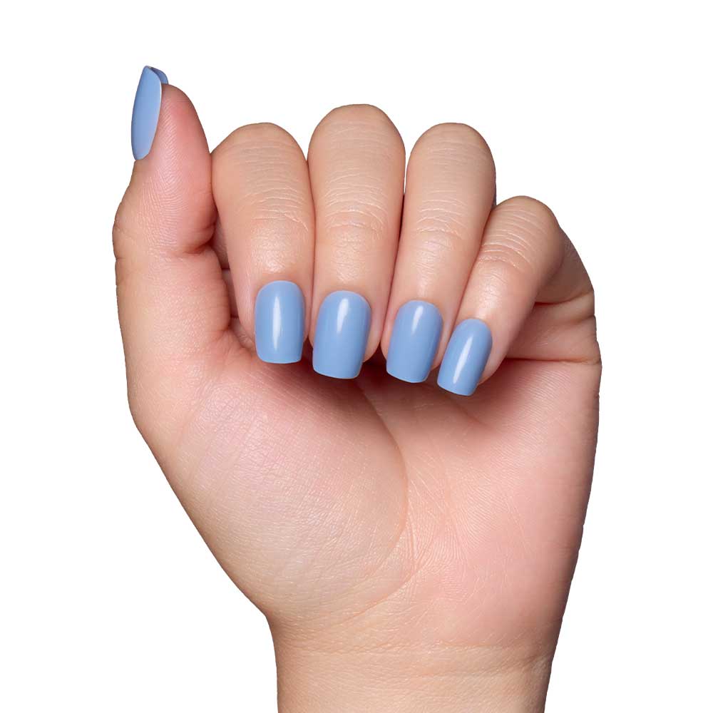 A hand with neatly manicured short squoval nails, painted in glamnetics Cashmere Blue vegan and cruelty-free nail set, exudes effortless elegance against a white background.