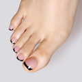 A close-up of a foot featuring Glamnetic press-on toenails in a chic black French tip design over a natural pink base.