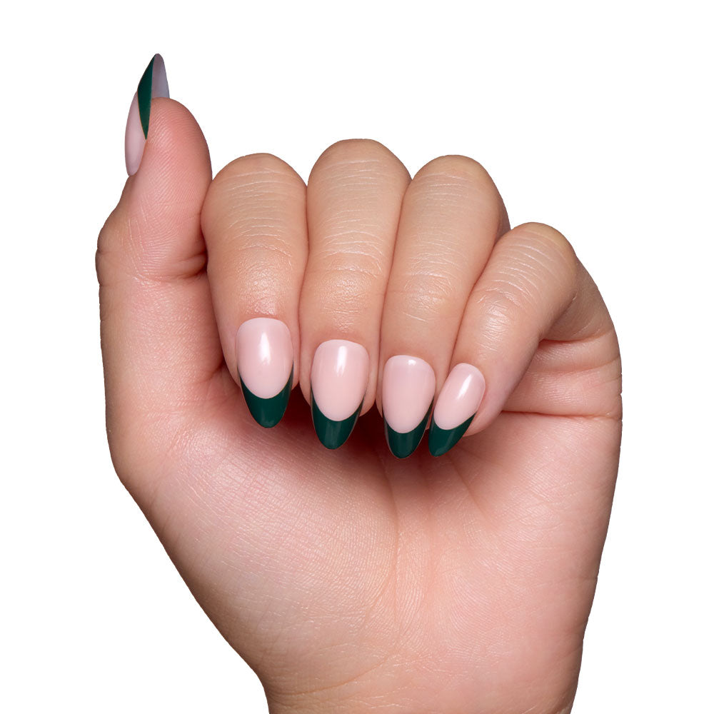 A hand with short almond nails features a dark green French tip, shown against a white background. The slightly clenched hand highlights the chic Château press-on nail set by glamnetic.