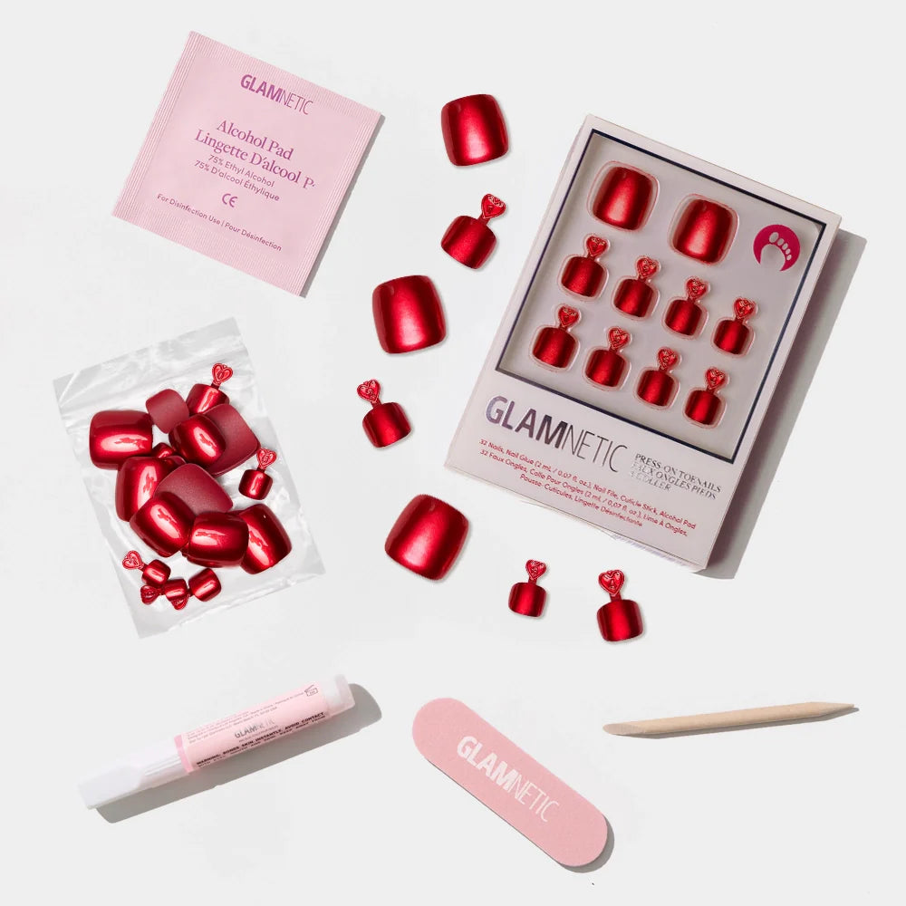 A flat-lay of the Glamnetic metallic ruby red press-on toenail kit with all nail prep and application tools.