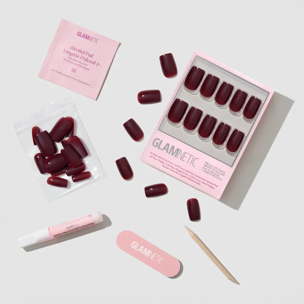 Cherry Mocha by glamnetic: medium square, cherry brown gloss press-on nails with pink nail file, wooden cuticle stick, nail glue, alcohol pad, and extra nails—vegan and cruelty-free formula. Arranged neatly on a white background.
