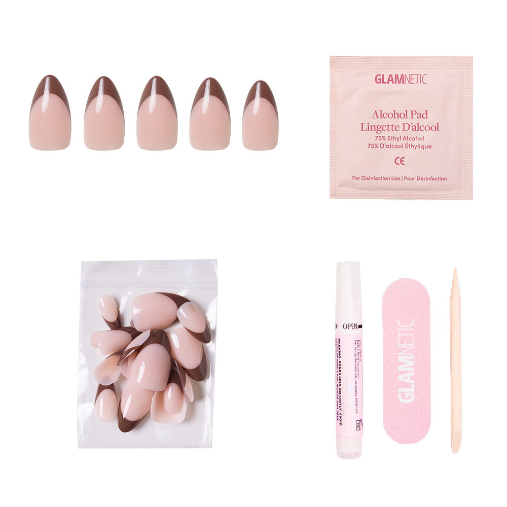 The glamnetic Chocolat press-on nails kit includes short almond nails in pink and earthy tones, an alcohol pad, extra nails in a plastic bag, a nail glue pen, a pink nail file, and a wooden cuticle stick on a white background.
