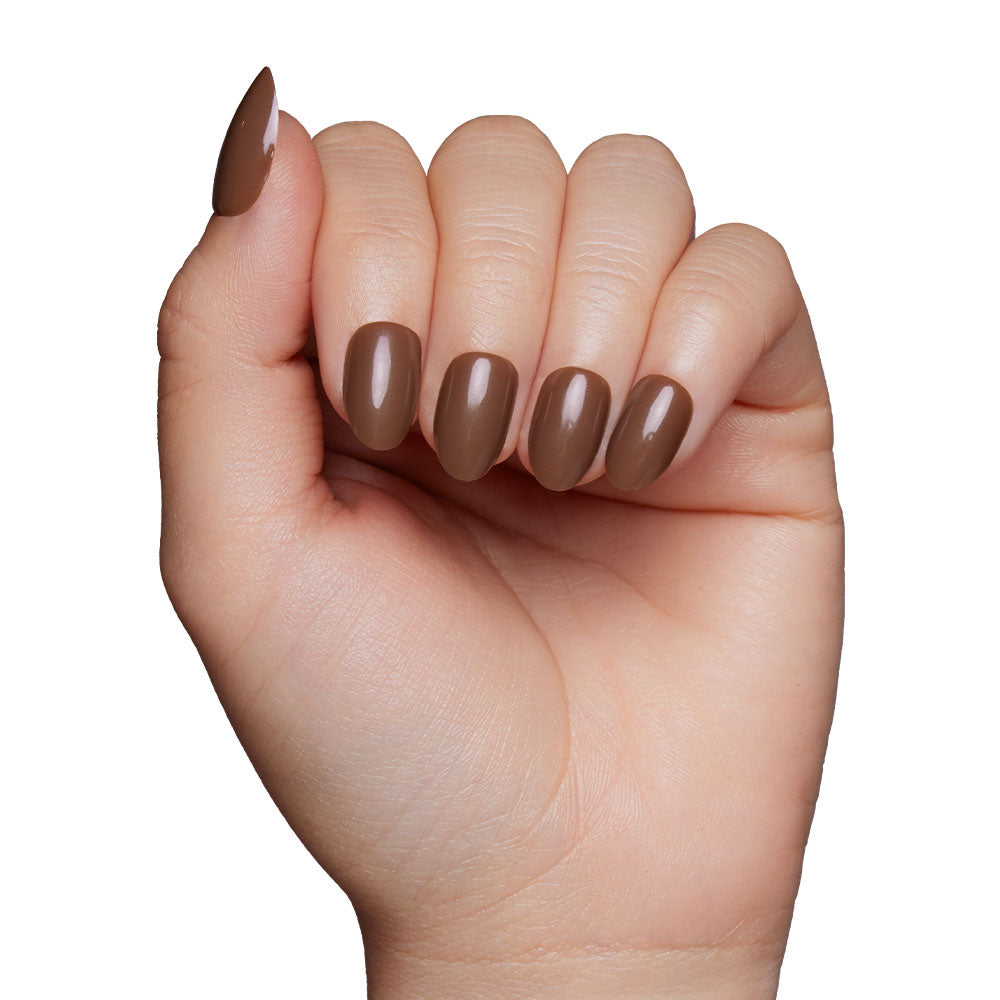 A hand with fingers curled inward displays neatly manicured glamnetic Press-On Nails in the shade Chocolate Brown, set against a plain white background.