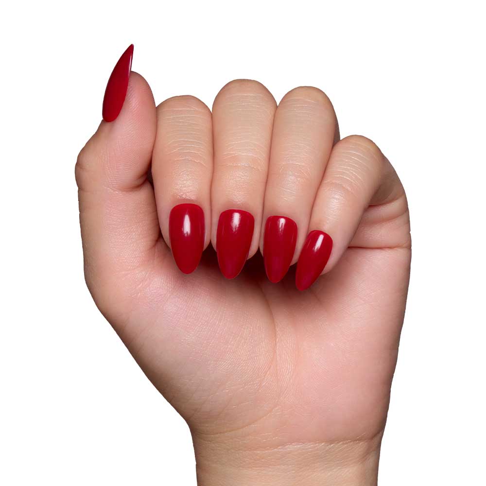 A hand with long, almond-shaped nails wears the glossy Classic Red set by glamnetic, displayed against a plain white background.