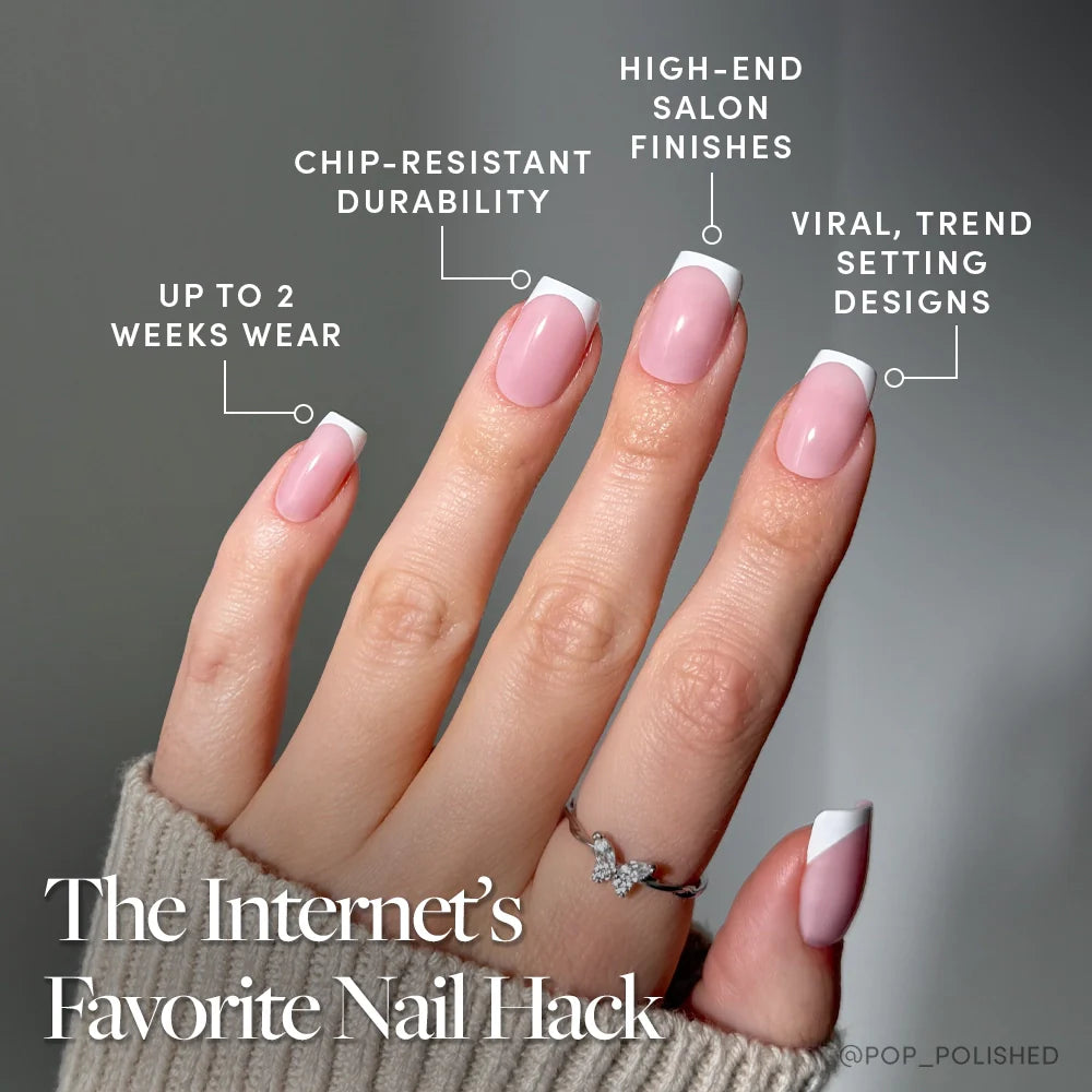 A hand with neatly manicured, pale pink Classy French nails by glamnetic features French tips and a modern twist. Benefits include up to 2 weeks wear, chip-resistant durability, salon-quality finish, and trend-setting style. A silver ring is worn.